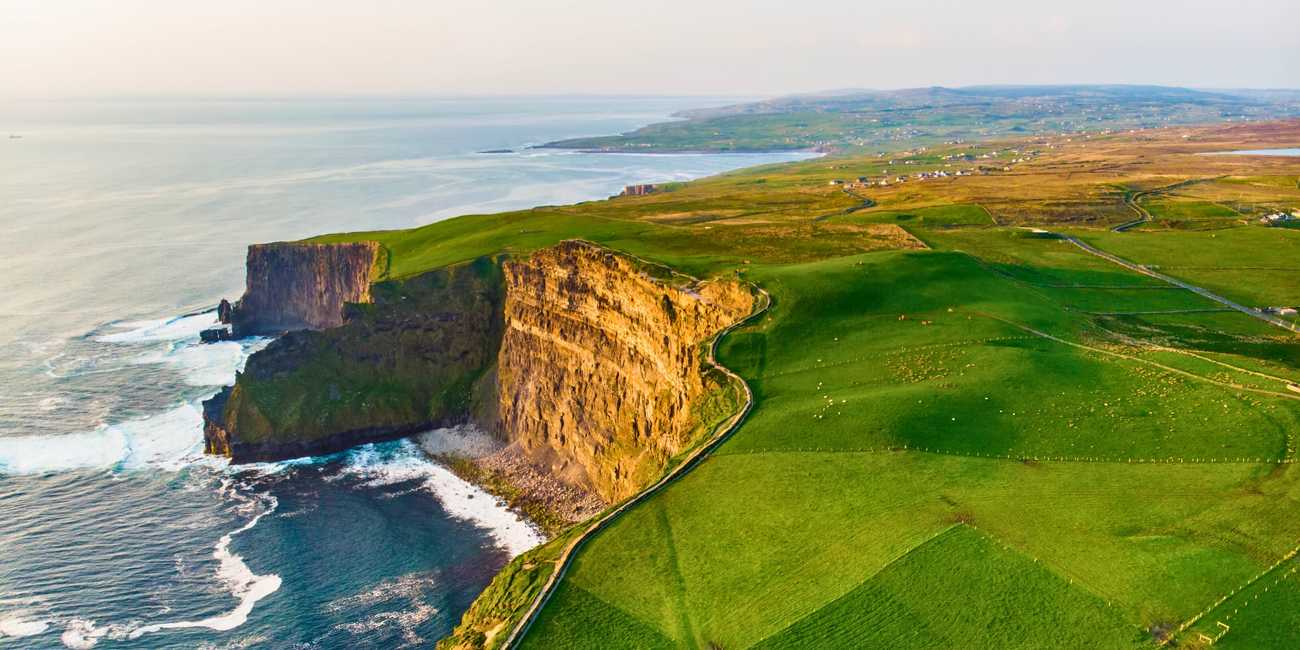 Explore the Edge of the World – Sunset at the Cliffs of Moher UNESCO Global Geopark in 2026 Aerial sunset view of the winding path and vertical rock faces of the Cliffs of Moher – Hiking the Wild Atlantic Way in in 2026